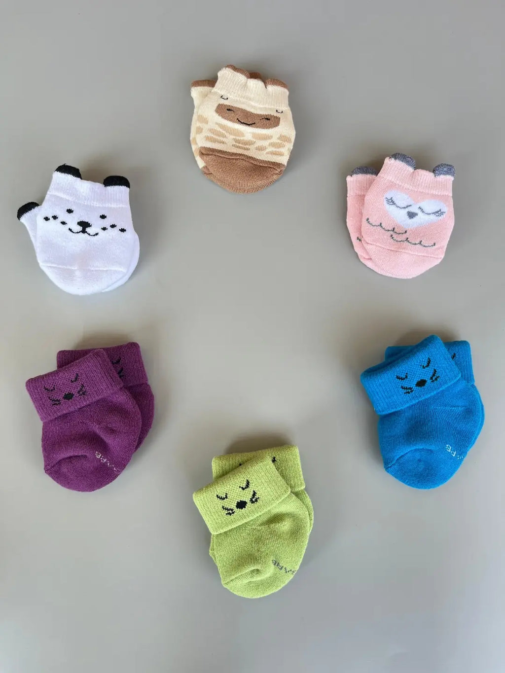 Air Garb baby combo socks for infants 0-1 years; a 6-pair collection arranged in a circle featuring animal faces like pink owl, brown giraffe, and white dog, alongside kitten-themed socks in purple, lime green, and blue.